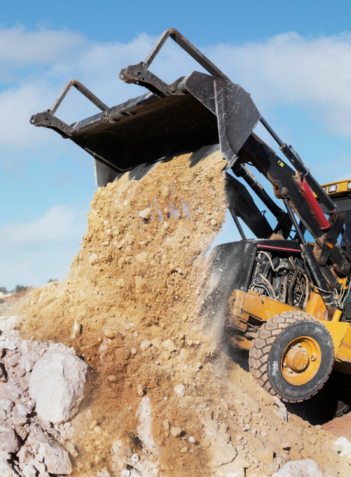 Engin de chantier déversant de la terre lors de travaux de terrassement